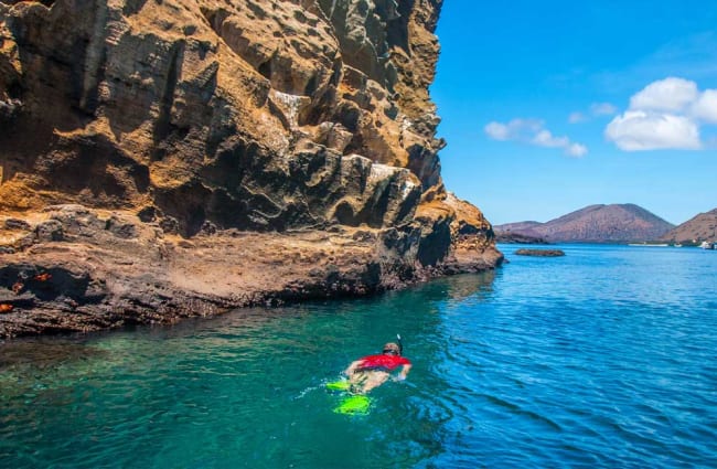 Person snorkeling by a large rock formation in Galapagos