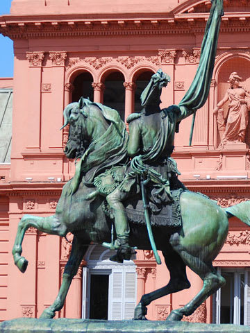 Statue of a horse rider in front of a red building