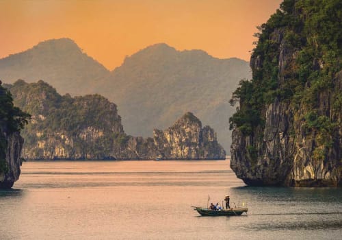 Small boat in Halong Bay at sunset